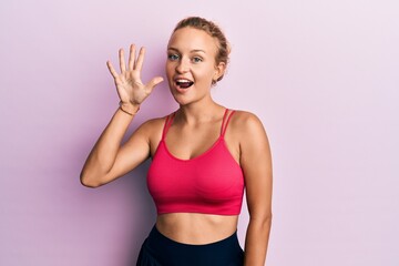 Beautiful caucasian woman wearing sportswear showing and pointing up with fingers number five while smiling confident and happy.