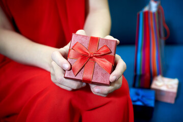 Female hands holding red gift box with a bow.