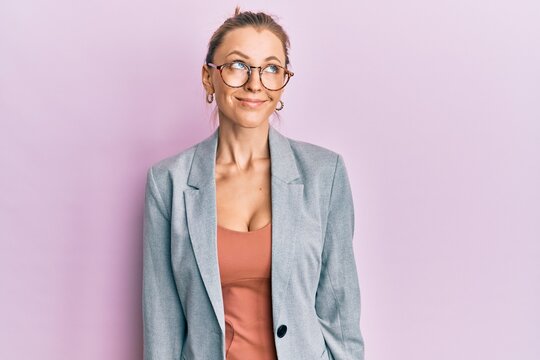Beautiful caucasian woman wearing business jacket and glasses smiling looking to the side and staring away thinking.