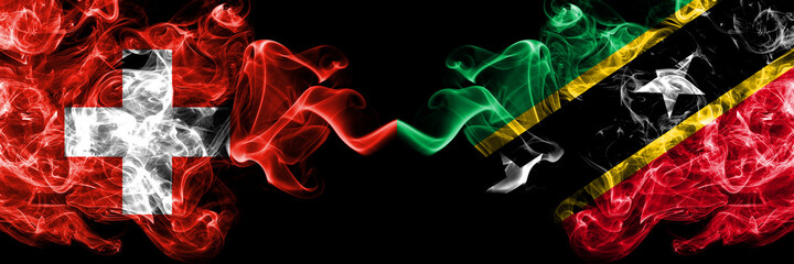 Switzerland, Swiss vs Saint Kitts and Nevis smoky mystic flags placed side by side. Thick colored silky abstract smoke flags.
