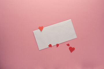 white envelope, red hearts on a pink background
