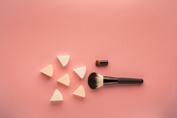 makeup brush and sponge on a pink surface top view