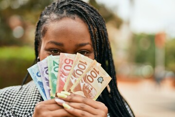 Young african american businesswoman smiling happy covering face with canadian dollars at the park.