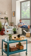 Man in the room, corner interior style, listening to the music with laptop and working from home. Modern decoration style.