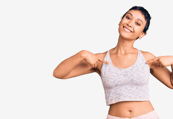 Fototapeta premium Young woman wearing sportswear looking confident with smile on face, pointing oneself with fingers proud and happy.
