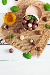 Macadamia nuts in shell with mint leaves and honey on wooden background