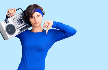Beautiful young woman with short hair wearing workout clothes and holding boombox with angry face, negative sign showing dislike with thumbs down, rejection concept