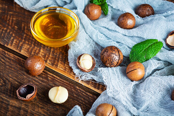 Fototapeta na wymiar Macadamia nuts in shell with mint leaves and honey on wooden background