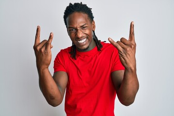 African american man with braids wearing casual clothes shouting with crazy expression doing rock symbol with hands up. music star. heavy concept.
