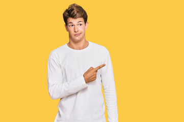 Handsome caucasian man wearing casual white sweater pointing aside worried and nervous with...