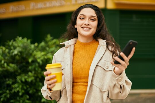Young middle east woman using smartphone drinking coffee at the city.