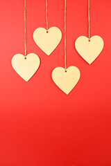 Valentine background. 4 wooden hearts hung with rope on a red background. Valentine concept. Flat view, top view, copy space