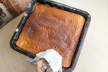 Girl holding a baking tray with baked dough. Cooking cake in the kitchen.