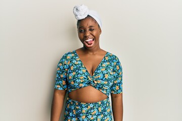 Young african woman wearing hair turban and african style winking looking at the camera with sexy...