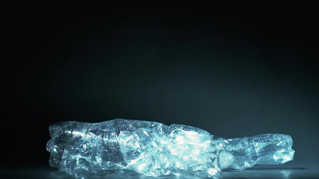 Zero waste. Biodegradable plastic. Climate change. Global warming. Empty used crushed eco bottles steaming up in air isolated on dark blue background.