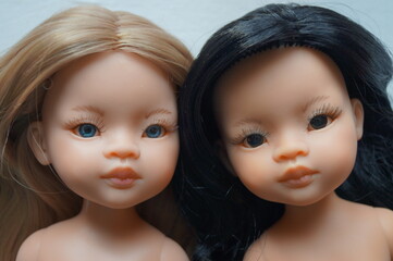 Close-up (macro) of the faces of two beautiful dolls (blonde and brunette). The eyes are blue and black.