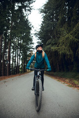 Cyclist girl with mountain bike pedaling on the road in Forest