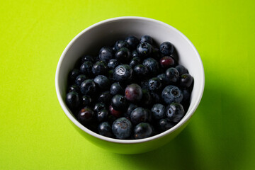 Fresh blueberries in a bowl with green background