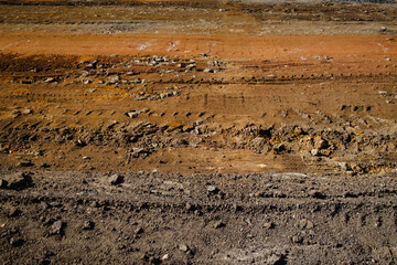 View of brown rough soil with vehicles tracks on the ground