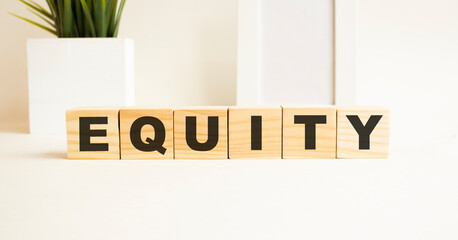 Wooden cubes with letters on a white table. The word is EQUITY. White background.