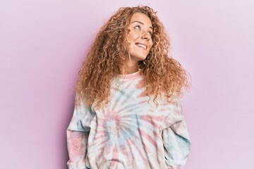 Beautiful caucasian teenager girl wearing casual tie dye sweatshirt looking away to side with smile on face, natural expression. laughing confident.