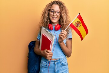 Beautiful caucasian teenager girl exchange student holding spanish flag smiling with a happy and...