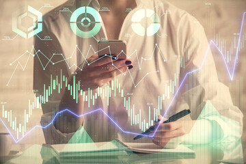 Double exposure of financial graph sketch hologram and woman holding and using a mobile device. Stock exchange concept.