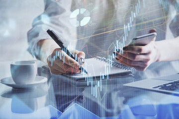Double exposure of financial graph sketch hologram and woman holding and using a mobile device. Stock exchange concept.