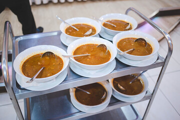 Selective focus shot of hot soup served in white bowls on a metal trolley