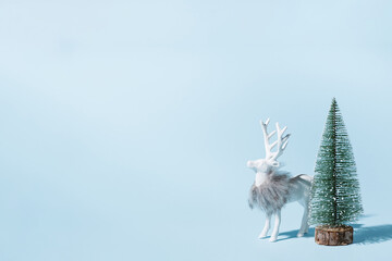 Creative Christmas reindeer with tree on pastel blue background minimalistic.  Modern Christmas card.