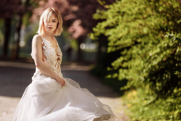 Fototapeta na wymiar woman's day. beautiful young woman in luxury long dress near blossoming of sakura. stylish girl near blossoming sakura flowers on background in the spring park. Harmony with nature concept
