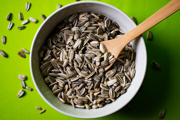 Sunflower seeds in a bowl with green background