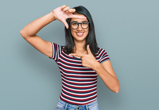 Beautiful asian young woman wearing casual clothes and glasses smiling making frame with hands and fingers with happy face. creativity and photography concept.