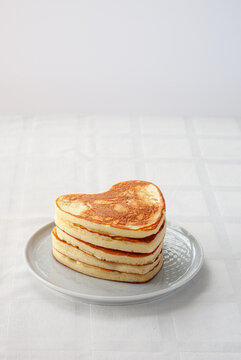 Pile of heart shaped pancakes on white background