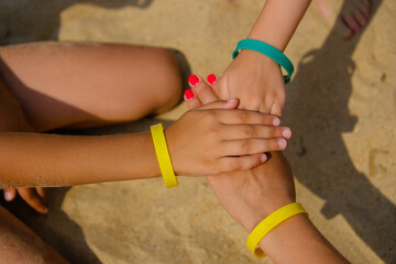 Family wearing color entrance wristbands of hotel resort or entertainment park at sand sea background.