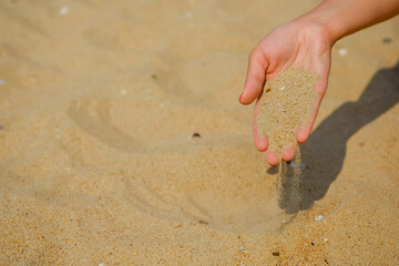 Young woman with sand in her hands on the sea beach.