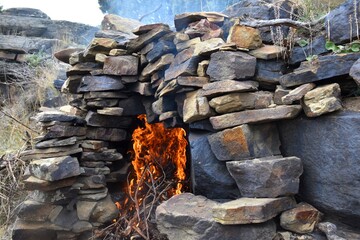 Bonfire with large flames in rock space to prevent fires. Rockrose firewood in Peroblasco, La Rioja, Spain.