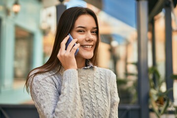 Young hispanic girl smiling happy talking on the smartphone at the city.