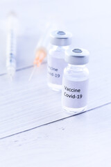 Close up of coronavirus vaccine and syringe on white background