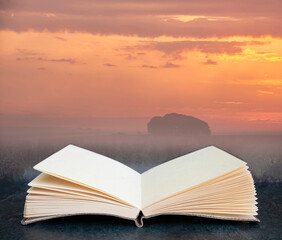 Digital composite of Stunning inspirational Summer sunrise landscape image over English countryside with mist hanging in fields in pages of open book