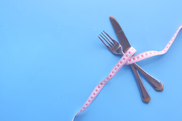 fork with measurement tape on blue background 