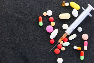 syringe and pills on dark background, close up 