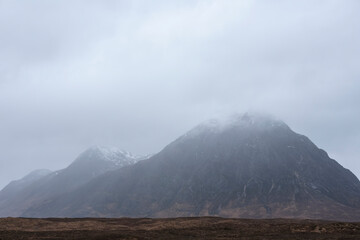 Stunning majestic landscape image of Buachaille Etive Mor and River Etive in Scottish Highlands on a Winter morning with moody sky and lighting