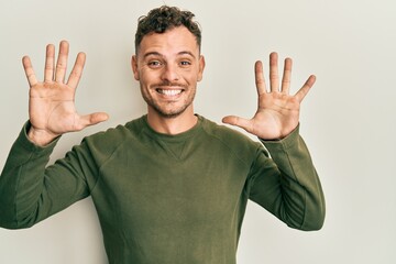 Fototapeta premium Young hispanic man wearing casual clothes showing and pointing up with fingers number ten while smiling confident and happy.