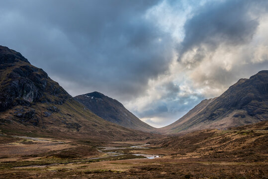 Majestic landscape image view down Glencoe Valley in Scottish Highlands with mountain ranges in dramatic Winter lighting