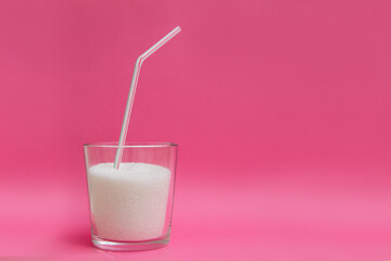 a glass of crumbly refined sugar with a drinking tube. the concept of sweet drinks