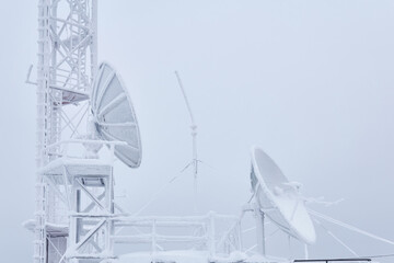 frosty parabolic antennas and the basement of the cell tower on the base radio station located in the highlands
