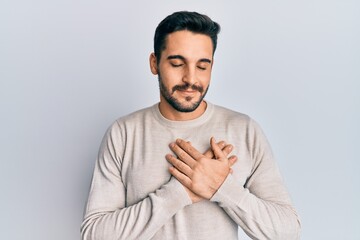 Young hispanic man wearing casual clothes smiling with hands on chest, eyes closed with grateful gesture on face. health concept.