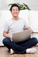 Cheerful businessman using a laptop computer on floorboard