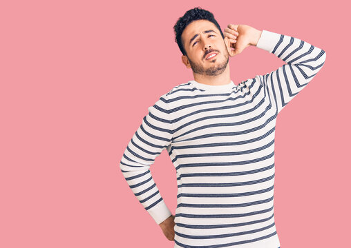 Young hispanic man wearing casual clothes stretching back, tired and relaxed, sleepy and yawning for early morning